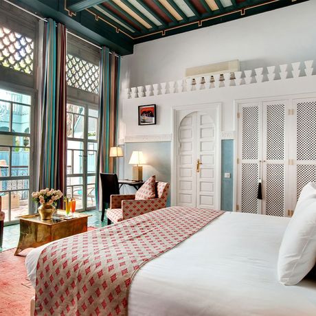Blick auf ein Bett und zwei Sessel an einer Fensterfront im Schlafbereich einer Suite Sultana
