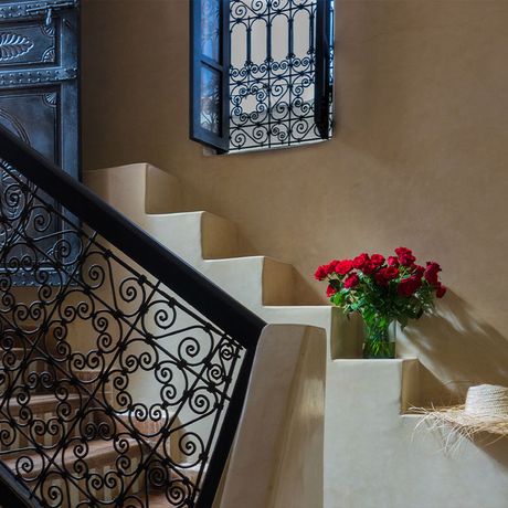 Blick auf frische Rosen und einen Strohhut an einer Treppe im Innenbereich des Riad Magellan