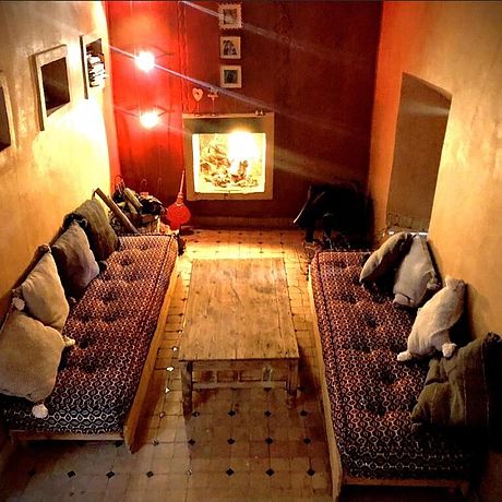 Maison J Galerie Blick ins Wohnzimmer mit angefeuertem Kamin