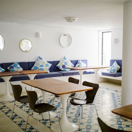 Blick auf Tische und Stuehle im Innenbereich des Hotels Vila Bea
