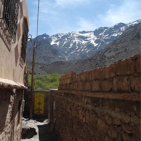 Blick entlang einer Mauer auf einen schneebedeckten Berg im Hohen Atlas