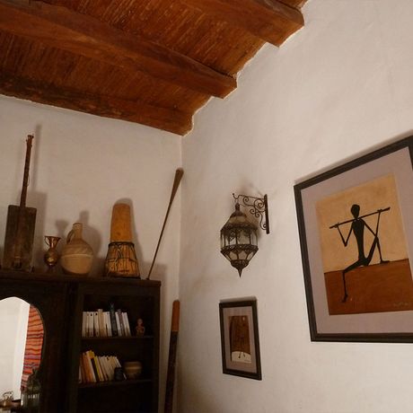 Blick auf ein Buecherregal mit Buechern und Deko, sowie zwei Bilder an einer Wand im Riad Cascades d´Ouzoud