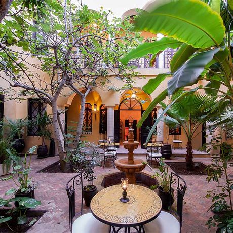 Blick auf Sitzmoeglichkeiten, Pflanzen und einen Springbrunnen im Innenhof des Riads Soleil d´Orient