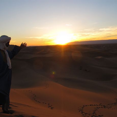 Blick auf eine Person bei Sonnenuntergang in den Duenen der Sahara