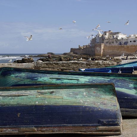 Blick auf blaue Boote am Strand von Essaouira mit der Stadt im Hintergrund