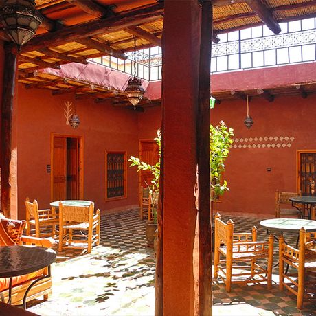 Blick auf einen Innenhof mit Tischen und Stuehlen im Kasbah-Hotel Petit Nomade zwischen
