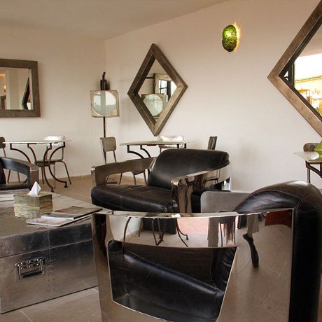 Blick auf einen Sitzbereich mit Sesseln, Stuehlen und Tischen im Riad Laaroussa