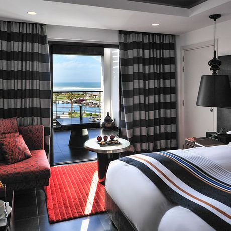 Blick auf ein Bett, eine Sitzecke und den Balkon des Superiorzimmers Pool- & Meerblick