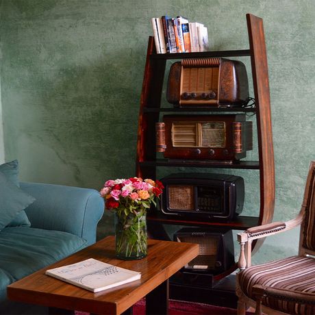 Blick auf ein Sofa une einen Sessel neben einem Regal mit antiken Radios im Innenbereich des Boutique-Hotels L´Iglesia