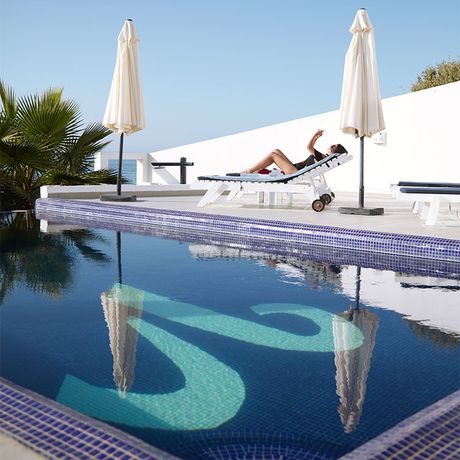 Blick auf eine Person auf einer Liege am Pool des Hotels Vila Bea