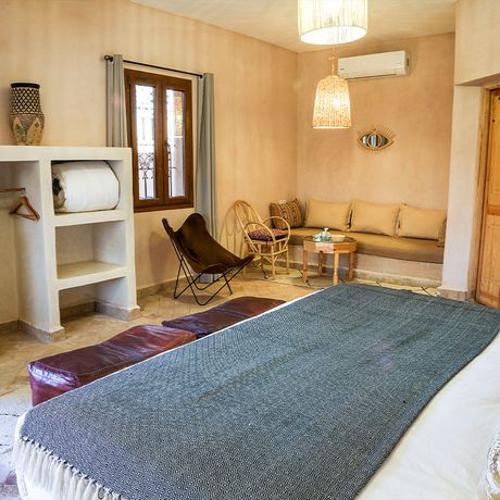 Blick auf ein Bett, ein Sofa und weitere Sitzmoeglichkeiten in einer Suite
