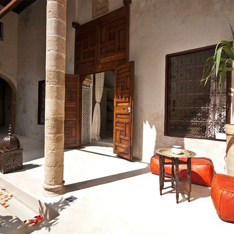 Blick auf einen Sitzbereich neben einer Holztuer im Innenhof des Riad el Maati