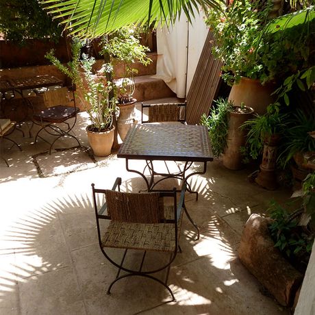 Blick auf Stuehle an Tischen neben Pflanzen im Aussenbereich des Riad Cascades d´Ouzoud