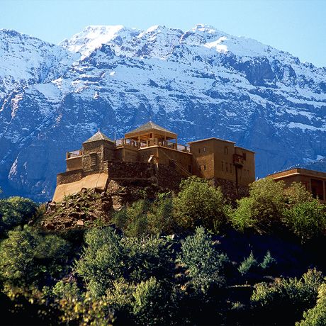 Blick auf das Kasbah-Hotel du Toubkal vor einem mit Schnee bedeckten Berg