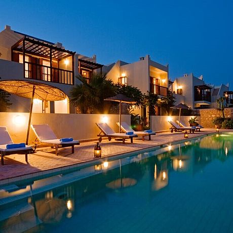 Rebali Riads Galerie Pool mit Abendbeleuchung und Villas im Hintergrund