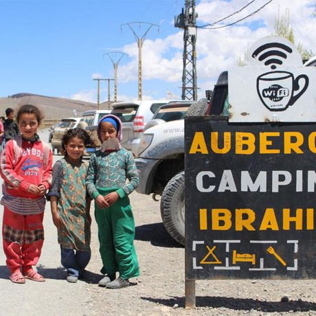 Blick auf Kinder neben einem Schild auf dem Parkplatz der Auberge Ibrahim