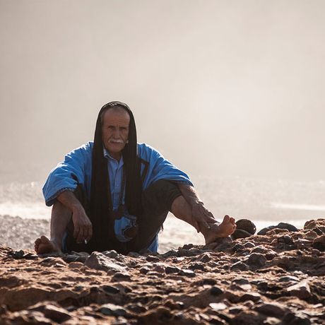 Blick auf eine sitzende Person am Strand Legzira