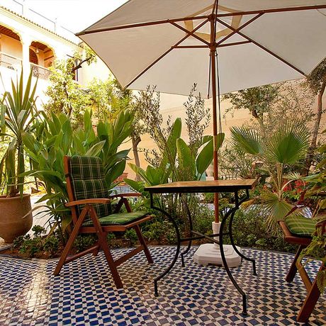 Blick auf einen Tisch mit zwei Stuehlen im Garten des Riad Salama