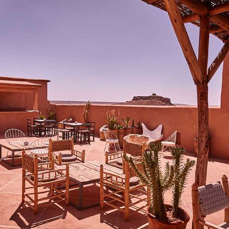Blick auf Stuehle an Tischen auf der Dachterrasse des Kasbah-Hotels Caravane