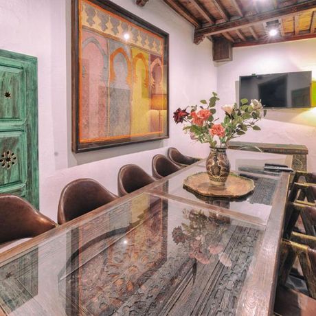 Blick auf einen langen Tisch mit Stuehlen im Innenbereich des Hotels Dar Baibou