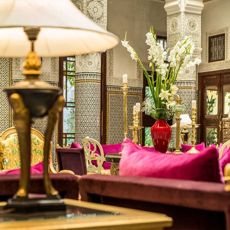 Blick auf Sofas und eine Tischlampe in einem Patio des Riad Fes