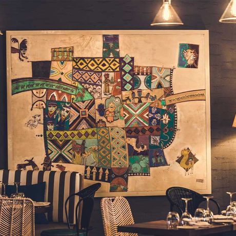 Blick auf gedeckte Tische und ein grosses Bild an einer Wand in einem Restaurant des Hotels Paradis Plage