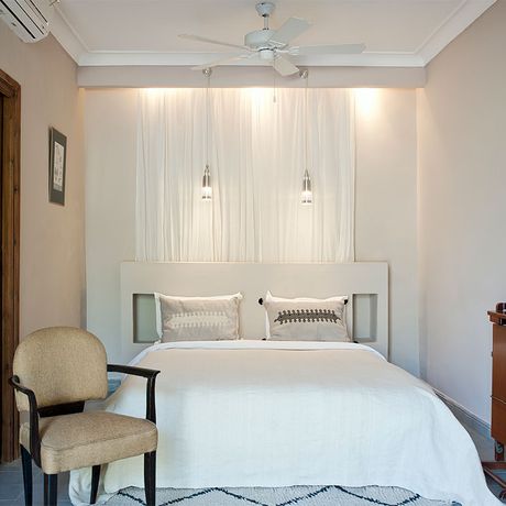 Blick auf ein Bett und einen Stuhl im Schlafbereich einer Suite