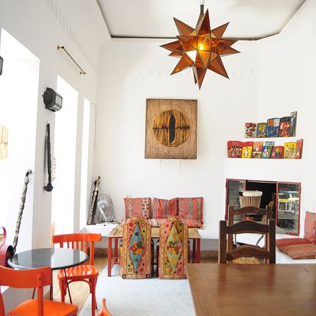 Blick in einen Raum mit verschiedener Deko und bunten Sitzmoeglichkeiten im Cafe Clock Marrakesch