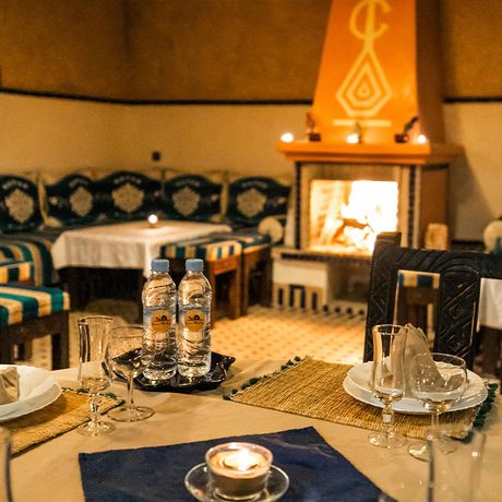 Blick auf gedeckte Tische und einen Kamin im Restaurant des Kasbah-Hotels Ksar Bicha