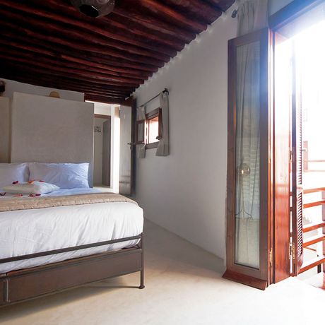 Blick auf ein Bett und den Zugang zum kleinen Balkon im Schlafbereich eines Deluxezimmers