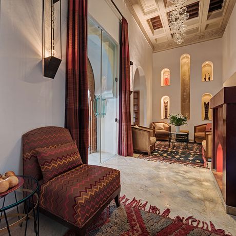 Blick auf Sessel und einen Kamin in einem Salon im Innenbereich des Riad Siwan