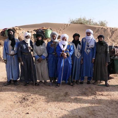 Eine Personengruppe vor einer Düne in der Sahara