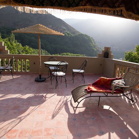 Blick auf die Terrasse mit Tischen, Stuehlen und Liegen im Hotel Jnane Imlil