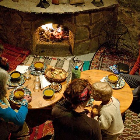 Blick auf eine Familie beim Abendessen vor einem Kamin in der Touda Ecolodge