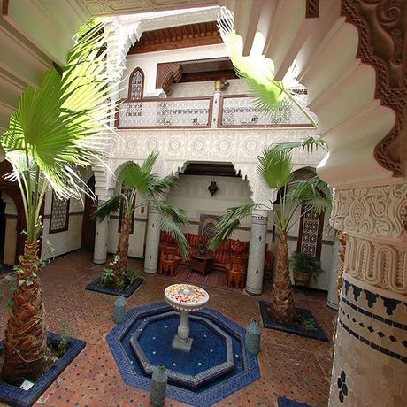 Blick auf Palmen und einen Springbrunnen im Innenhof des Riad Dar Al Kounouz