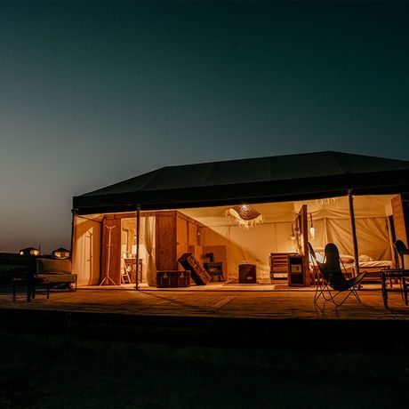 Blick auf ein beleuchtetes Zelt bei einer Wuestenuebernachtung