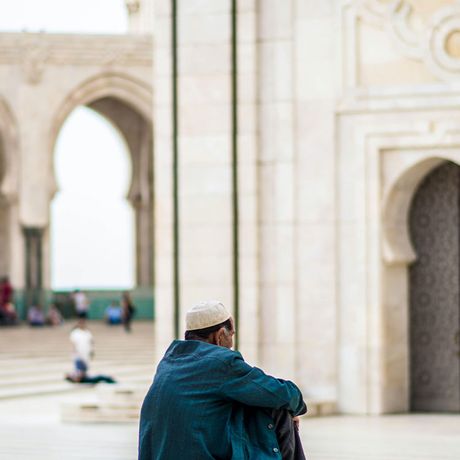 Blick auf eine sitzende Person vor der Moschee Hassan II