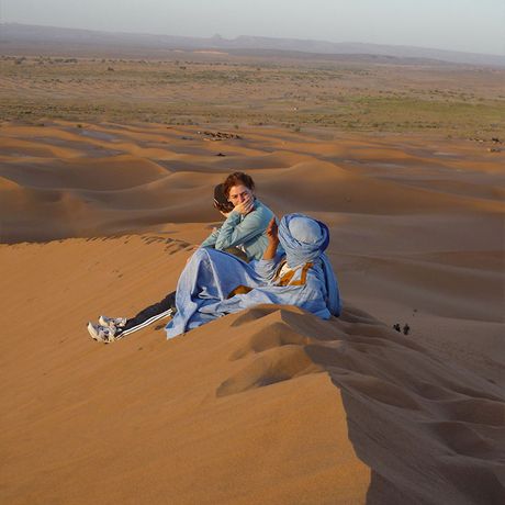 Blick auf eine Ausflugsgruppe mit ihrem Reiseleiter in den Duenen der Wueste Marokkos