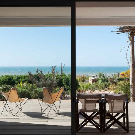 Blick auf Stuehle und einen Tisch auf einer Terrasse mit Meerblick des Hotels Azalai Beach Cottage