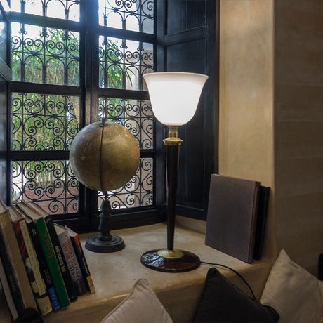 Blick auf eine Lampe, einen Globus und Buecher vor einem Fenster des Riad Magellan