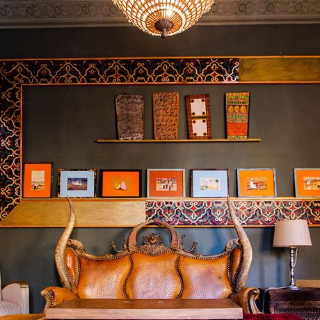 Blick auf ein Sofa und Sessel vor einer Wand mit Bildern und Deko im Innenbereich des Kasbah-Hotels Dar Tourkia