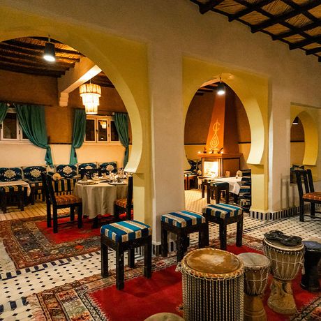 Blick auf gedeckte Tische, Trommeln und einen Kamin im Restaurant des Kasbah-Hotels Ksar Bicha