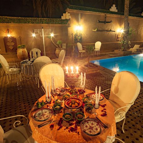 Blick auf zwei gedeckte Tische zum Abendessen am Pool des Boutique-Hotels Riad Dar Sofian