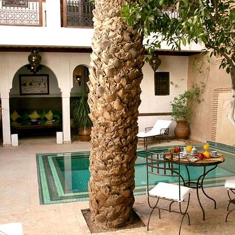 Blick auf einen gedeckten Fruehstueckstisch am Pool des Riad Palmier